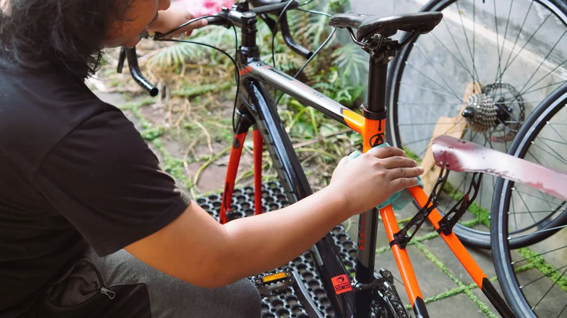 Rinçage d'un vélo de route à la douchette dans une salle de bain